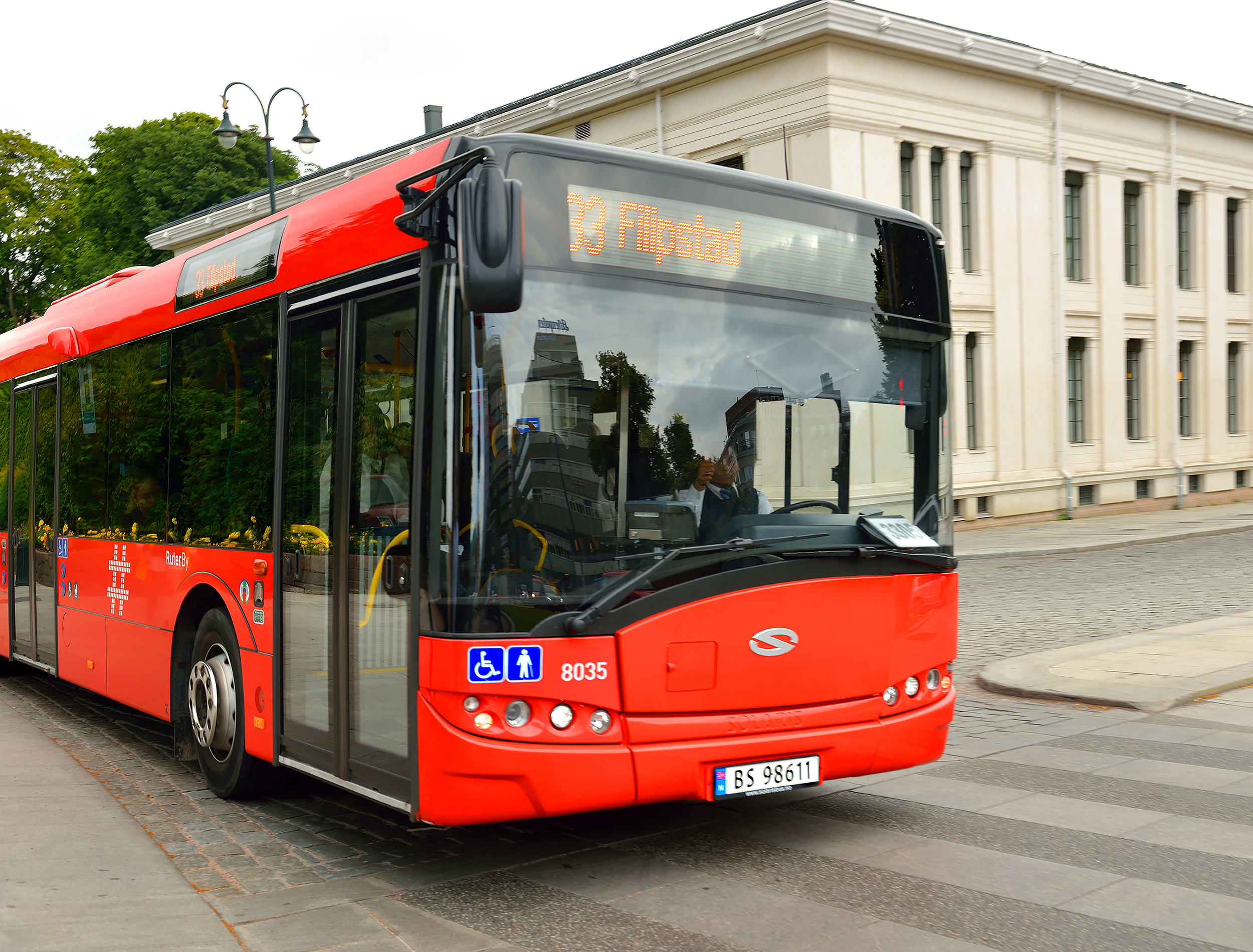 Red bus driving down street. Oslo, Norway