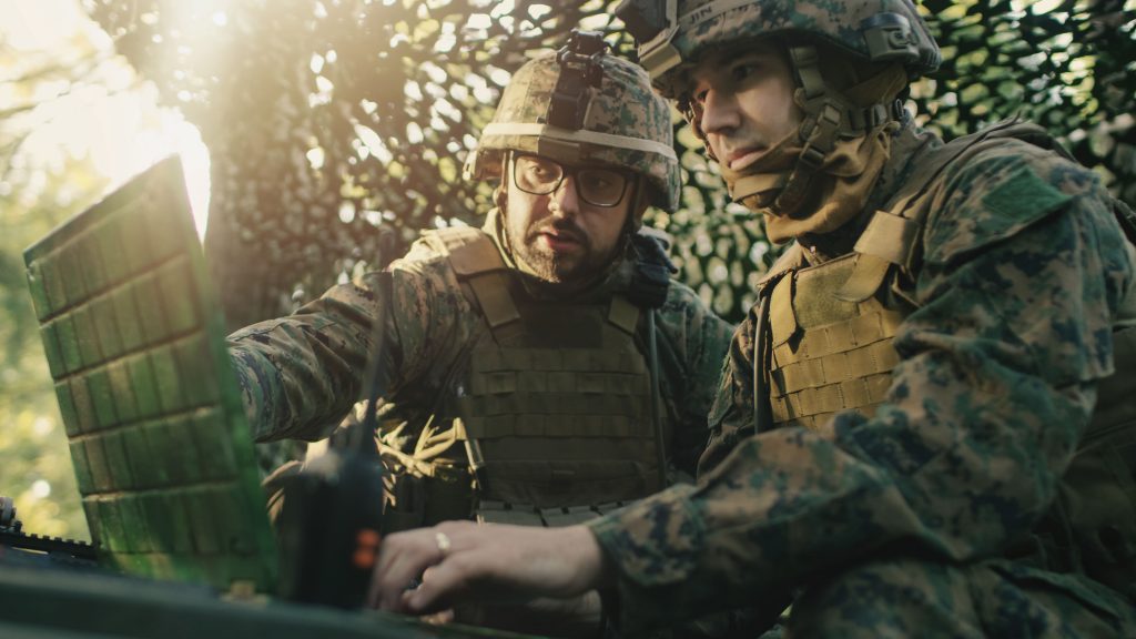 Military Staging Base, Officer Gives Orders to Chief Engineer, They Use Radio and Army Grade Laptop. They're in Camouflaged Tent in a Forest. They're on Reconnaissance Operation/ Mission.